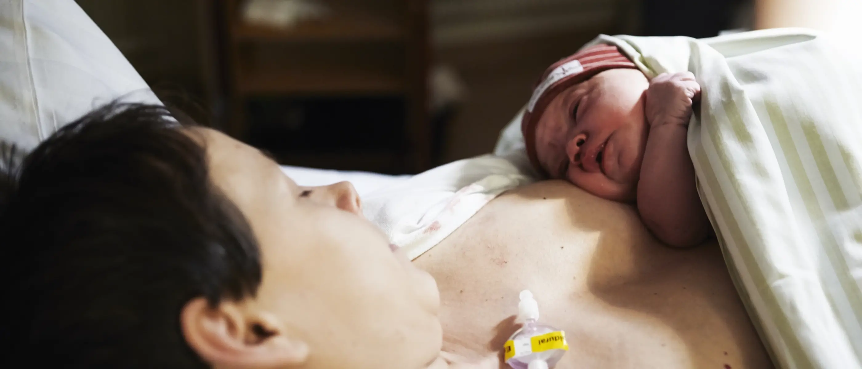 En nyfödd bebis vilar i sin mammas famn.