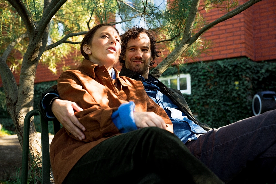 Par i 30-årsåldern sitter utomhus och håller om varann.