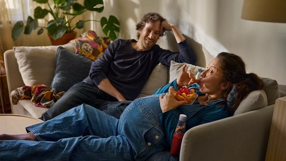 Höggravid kvinna sitter med sin partner i soffan.