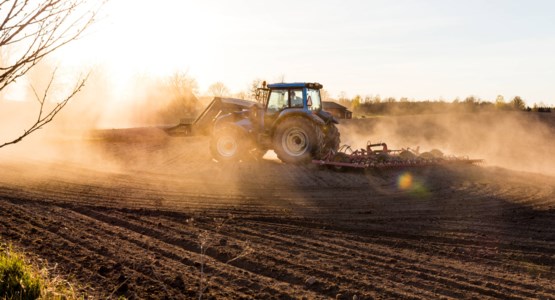 Traktor på åker, fotografi.