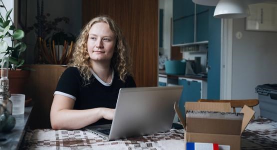 En tjej sitter vid ett bord med en dator.