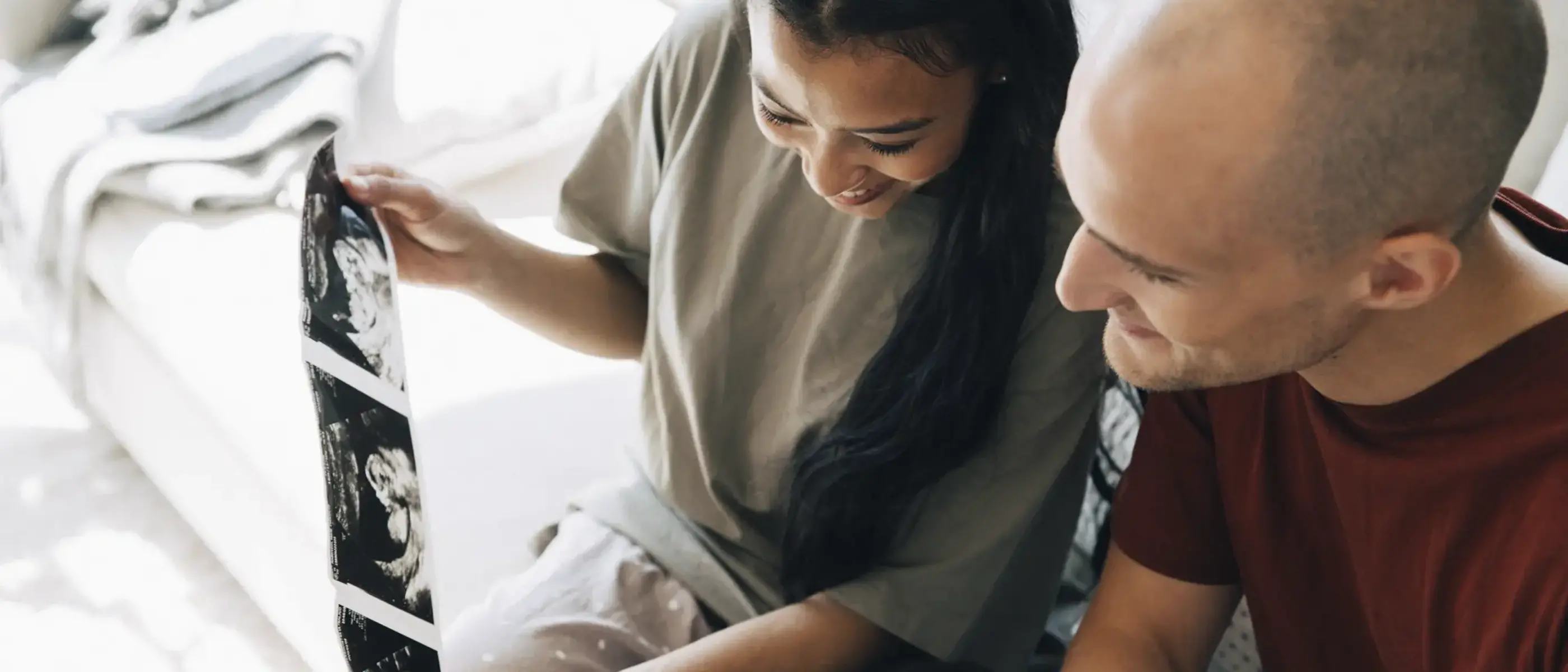 En gravid kvinna och hennes partner tittar på bilder från ultraljudet.