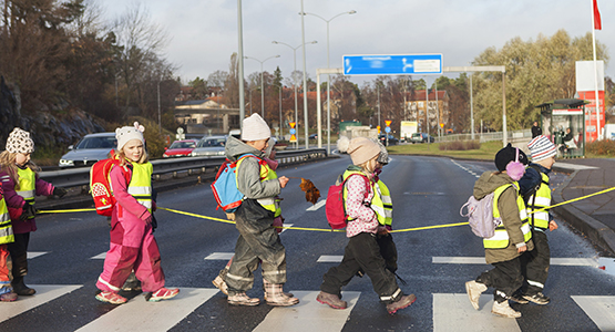 Barn i reflexvästar passerar ett övergångsställe.