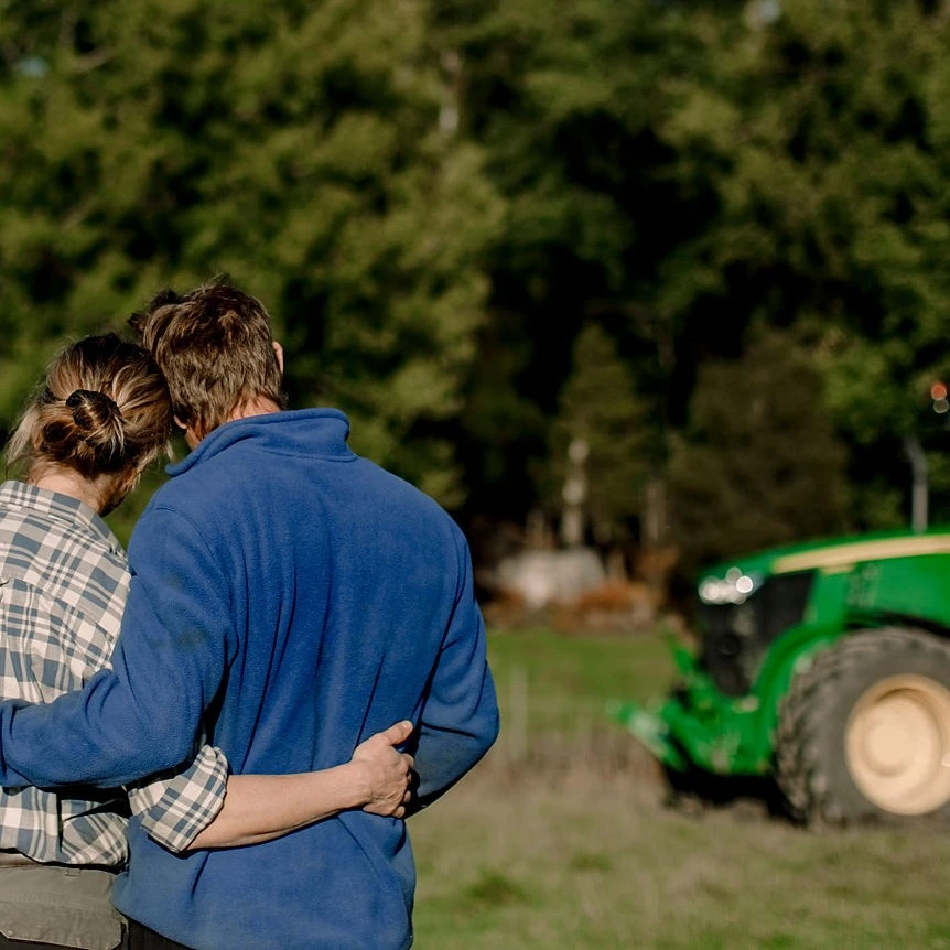 Par håller om varandra på en åker traktor syns