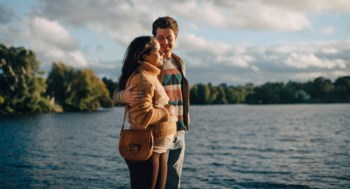 En gravid kvinna står bredvid sin partner och blickar ut över vattnet.