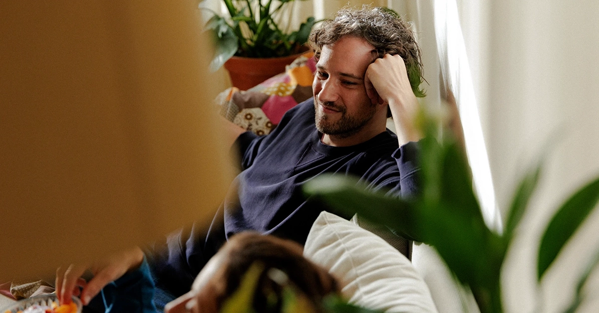 Man som sitter skönt i en soffa.