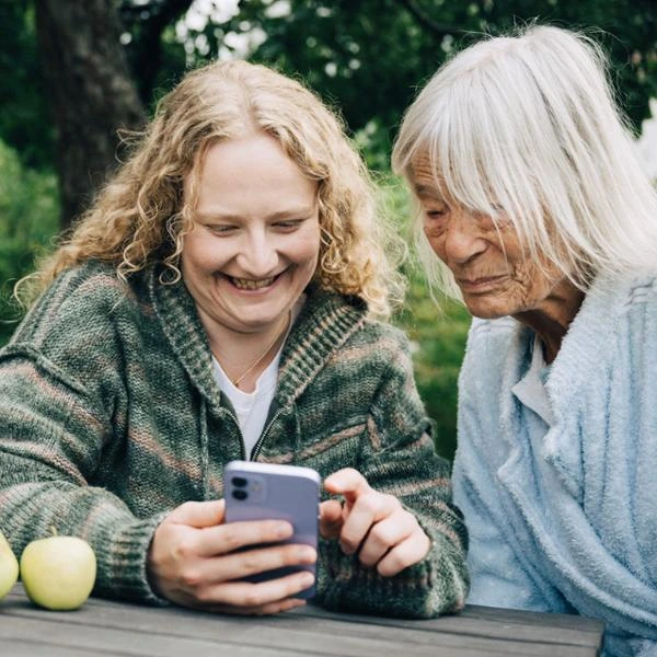 Två kvinnor kollar i mobilen