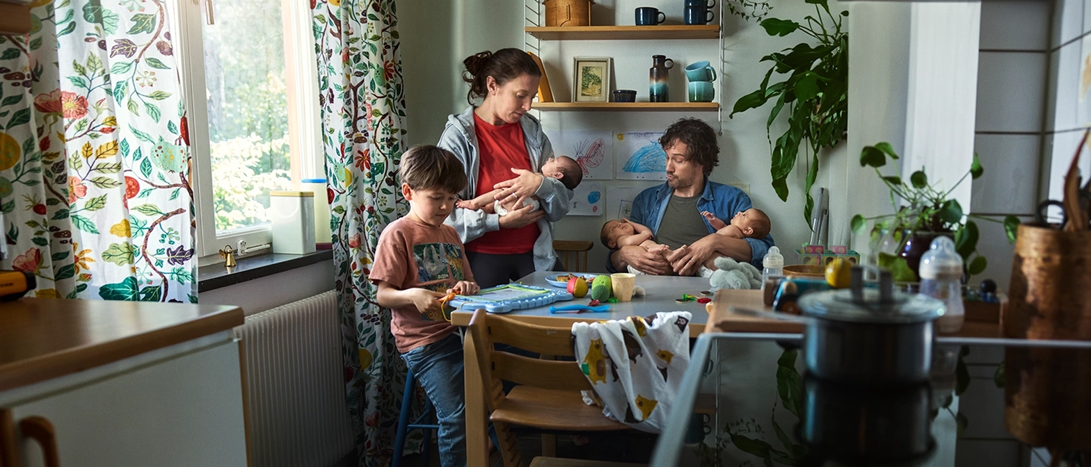 Familj med nyfödda trillingar sitter i köket och funderar på lånelöfte för ett större boende.