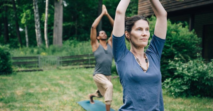 Två personer yogar utomhus.