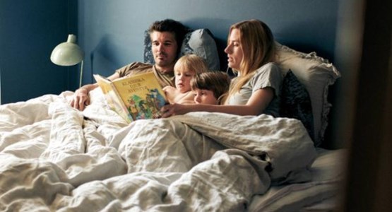 Familj läser godnattsaga i sängen. 