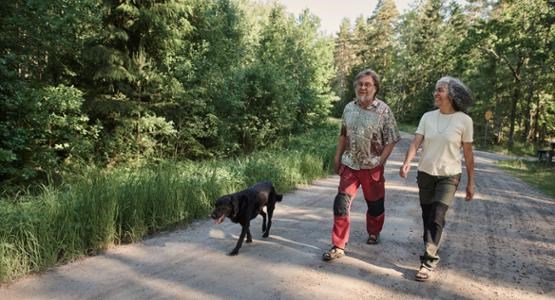 Äldre par på hundpromenad. 