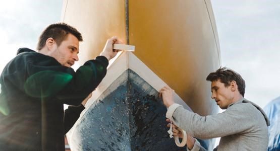 Killar bottenmålar segelbåt.