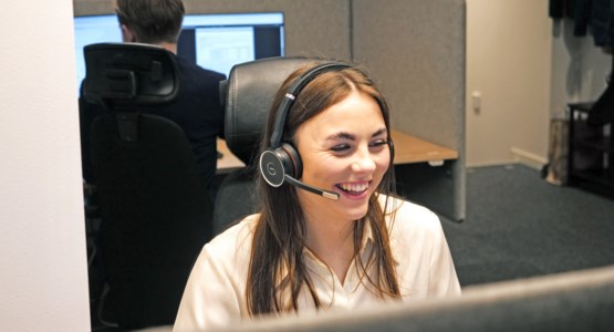 Glad medarbetare hjälper kund i telefon.