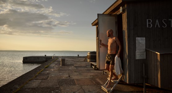 En man står utanför en bastu och ska bada