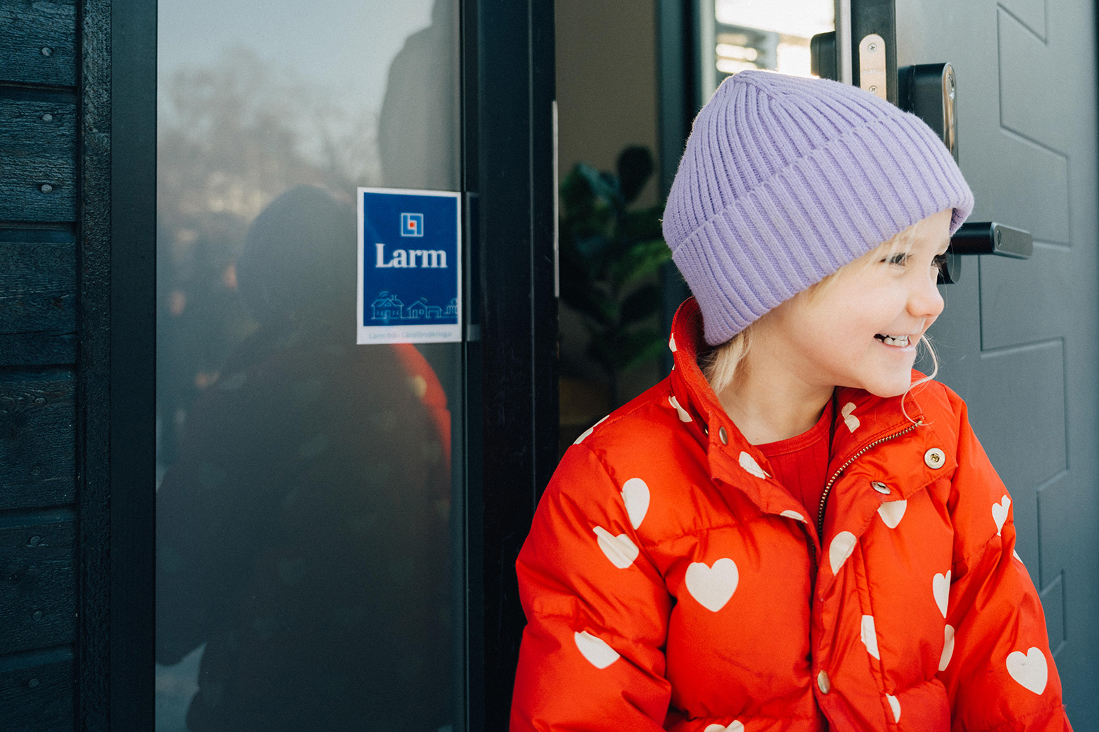 Barn står vid ytterdörr med larmdekal.