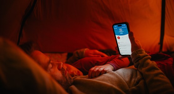Person med telefon i ett tält, foto