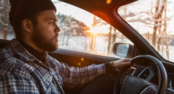 Man kör bil i vinterlandskap