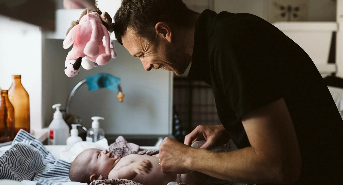 Pappa byter blöja på bebis.