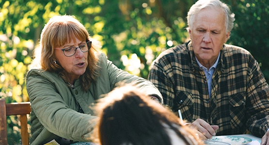 Ett par i pensionsåldern umgås med sitt barnbarn utomhus.