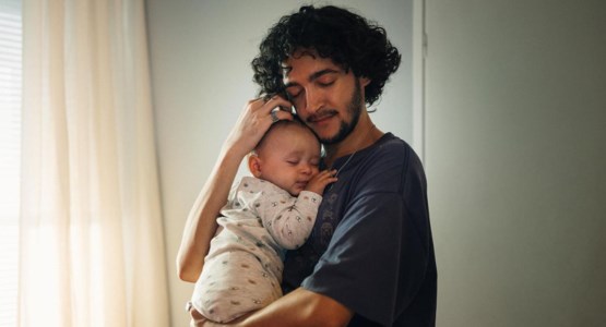 Ung kille som håller en liten bebis i famnen. 