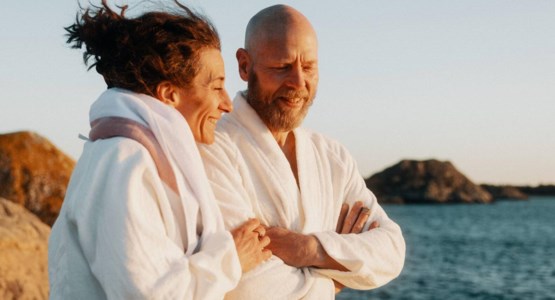 Par står på klippor vid havet i badrockar