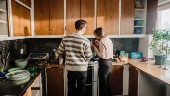 En kille och tjej lagar mat i ett lägenhetskök.