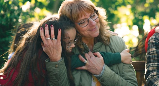 Äldre kvinna kramar om sitt barnbarn.