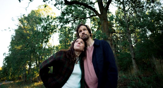 Man och kvinna håller om varandra i parkmiljö.