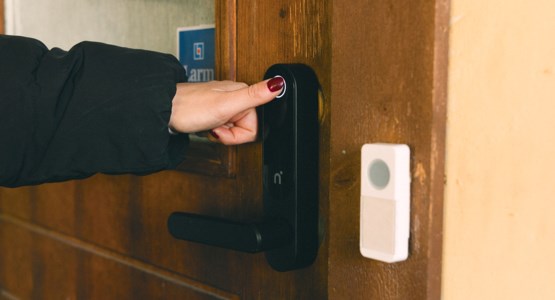 Kvinna låser upp dörr med hjälp av fingeravtryck.